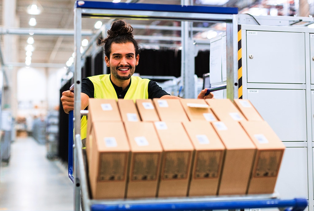 Postal Service employee pushing cart of packages